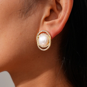 Detail view of a vintage pearl stud earring with a gold base and sparkling rhinestones