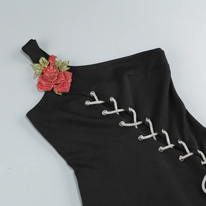Détail d'une robe noire asymétrique avec roses 3D et laçage en strass étincelants
