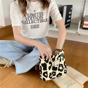 Lifestyle view of stylish leopard print canvas tote bag on wooden floor background