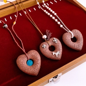 Detail of red heart lava stone pendants with silver cross accents on velvet lining