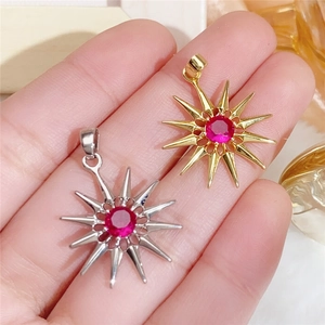 Macro detail of gold and silver starburst pendants with red zircon inlay on palm