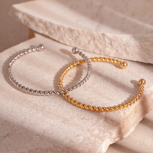 Minimalist twisted rope open bangle set in gold and silver finish on stone display