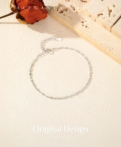 Detail of S925 sterling silver chain with white beads on a beige textured background