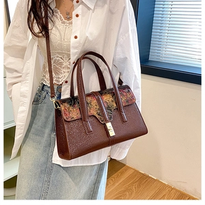 Detail of vintage brown crossbody bag with artistic flap pattern and metal lock on model