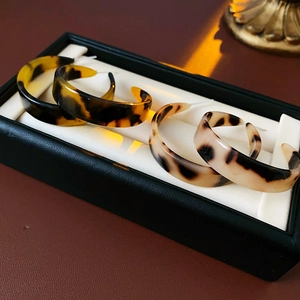 Detailed view of resin C-shape hoop earrings with tortoiseshell and leopard print patterns