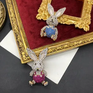 Detail view of rabbit brooches with blue and pink rhinestones on red velvet background