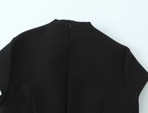Detail shot of the stand collar and invisible zipper on the black polka dot mini dress