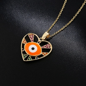 Golden heart pendant necklace with colorful gems and orange evil eye on black background