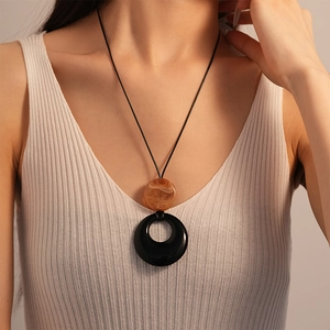 Detail of vintage resin double circle pendant on a black cord necklace worn by a model