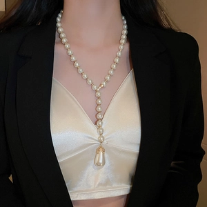 Close-up of elegant Y-shaped pearl necklace with large teardrop pendant on a model