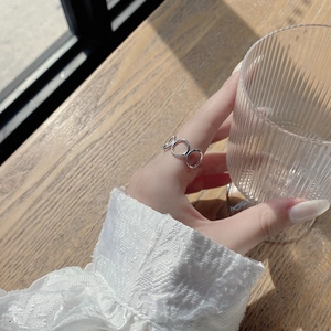 Detail of s925 silver interlocking circle ring worn while holding a glass cup