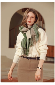 Detailed close-up of soft green and beige plaid scarf texture with elegant fringe tassels