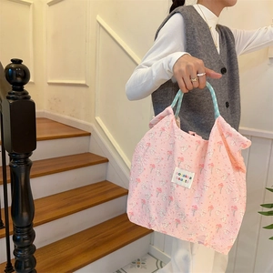Detail of pink canvas tote featuring embossed rabbit patterns and blue striped handles