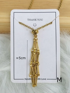 Close-up of golden tassel necklace pendant with bead detail on a handmade display card