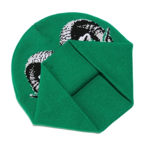Close-up of green knitted beanie featuring black and white animal jacquard patterns