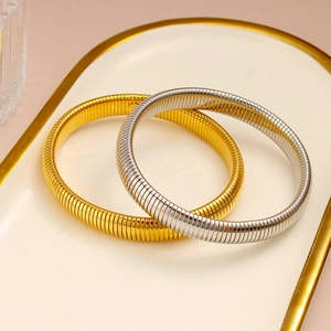 Vista superior de pulseras de acero inoxidable doradas y plateadas en bandeja de cerámica