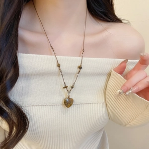 Dettaglio di un ciondolo a cuore in occhio di tigre marrone su una collana con perline