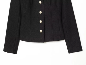 Close-up of black tweed texture and golden embossed buttons on a slim-fit blazer