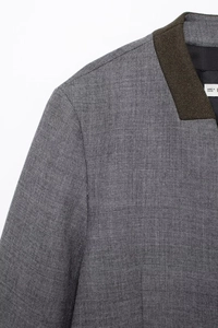 Detail of grey jacket shoulder with dark contrast collar and fine fabric texture