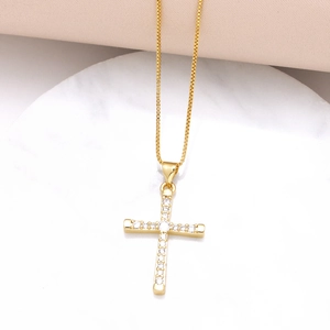 Gold plated cross pendant necklace with sparkling cubic zirconia on a marble base
