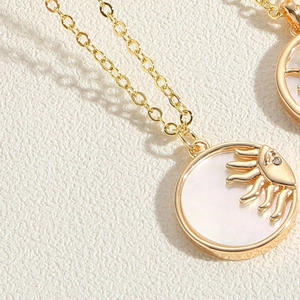 Détail du collier avec pendentif soleil doré et nacre avec un accent de zircon