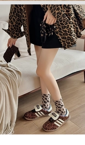 Close-up of leopard print mid-calf knit socks paired with matching sneakers and jacket