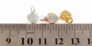 Macro detail of 10mm gold-plated heart pendants with clear crystals on a scale