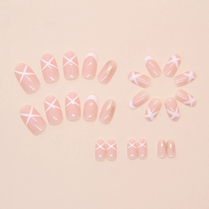 Detail of nude pink press-on nails with white French tips and crisscross glitter designs