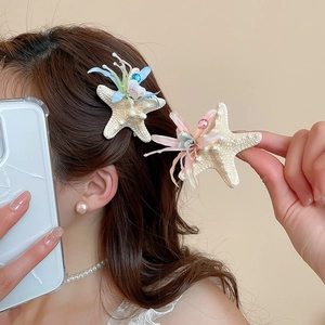 Detail of starfish hair clips with fabric flowers and beads worn on model's hair