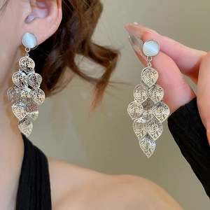 Detailed view of silver leaf tassel earrings with white opal stone and hollow metal texture