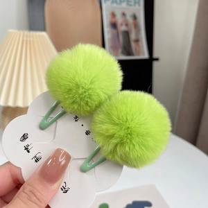 Close-up of a pair of fluffy neon green rabbit fur mini hair clips on a display card