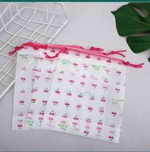 Frosted drawstring bag with cherry print and pink rope in a lifestyle setting