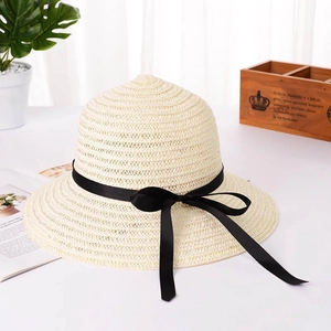Vista dettagliata di un cappello di paglia beige con fiocco nero e trama traforata.