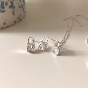 Detailed view of silver padlock pendant necklace and earrings set with cubic zirconia