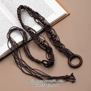 Detailed close-up of dark brown woven belt with wooden beads and buckle on vintage book
