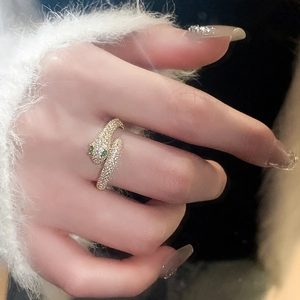 Close-up of gold plated snake ring with green gemstone eyes and cubic zirconia