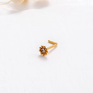 L-shaped gold nose stud with a floral design and a central white sparkling crystal