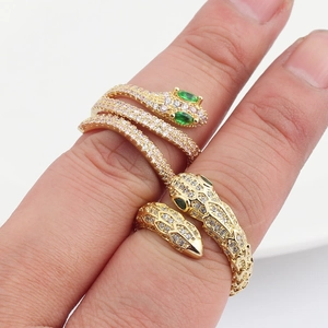 Anello a serpente dorato con zirconi bianchi e occhi in gemma verde sulla mano