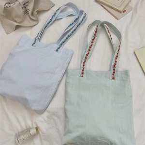 Detailed look at canvas tote bags with delicate floral embroidery on the handles