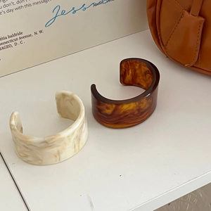 Details von unregelmäßigen breiten Acryl-Armreifen in Marmorweiß und Schildpatt-Optik
