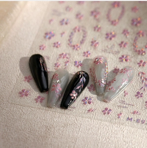 Detailed macro view of floral nail stickers with pink laser cherry blossom patterns