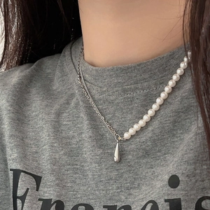 Close-up of asymmetrical necklace featuring half white pearls and half silver chain on model