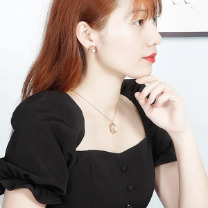 Gros plan d'un ensemble collier et boucles d'oreilles en or rose avec étoiles et perles