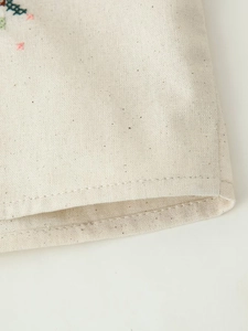 Vue macro détaillée de la texture du lin beige et des points de broderie colorés