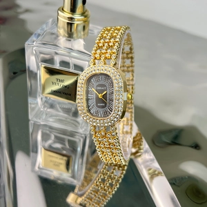 Detailed view of luxury gold oval quartz watch with rhinestones on a reflective surface