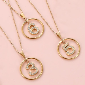 Detailed view of three gold necklaces with zircon-studded number 3, 5, and 6 pendants