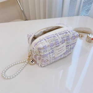 Detail of tweed vanity bag with gold zipper and elegant pearl handle with bow ornament