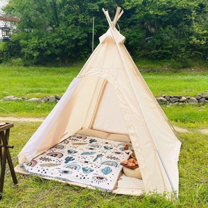 Detail of bohemian outdoor teepee tent with ethnic patterned rug on a lush green lawn