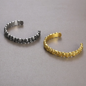 Detail of gothic skull cuff bracelets in gold and vintage black stainless steel finish