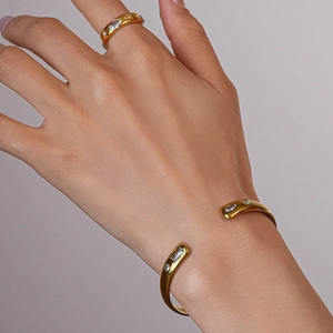 Macro detail of gold adjustable sunburst cuff and zircon ring worn on a female wrist